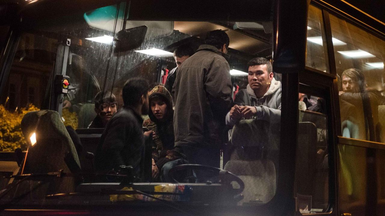 Flüchtlinge, die zuvor mit einem Sonderzug angekommen waren, sitzen in Freiberg in einem Bus und warten auf die Weiterfahrt.