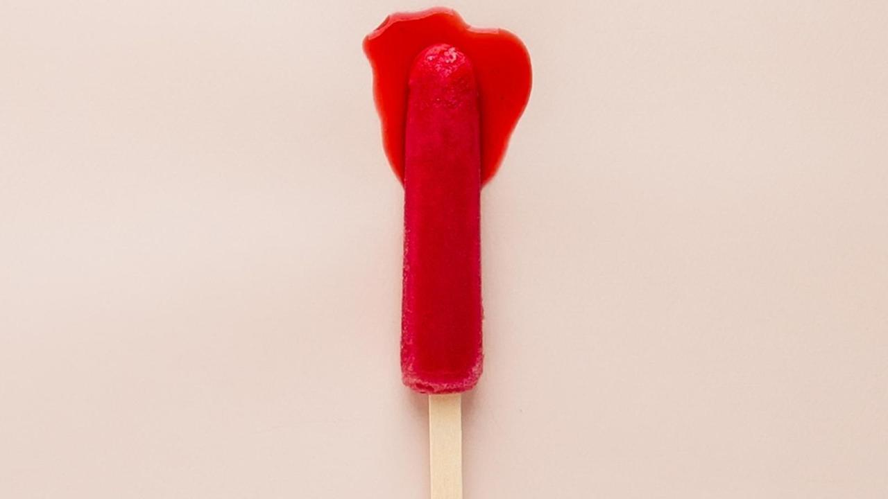 Ein rotes Eis an einem Stiel schmilzt. Ein rotes Eis an einem Stiel schmilzt.