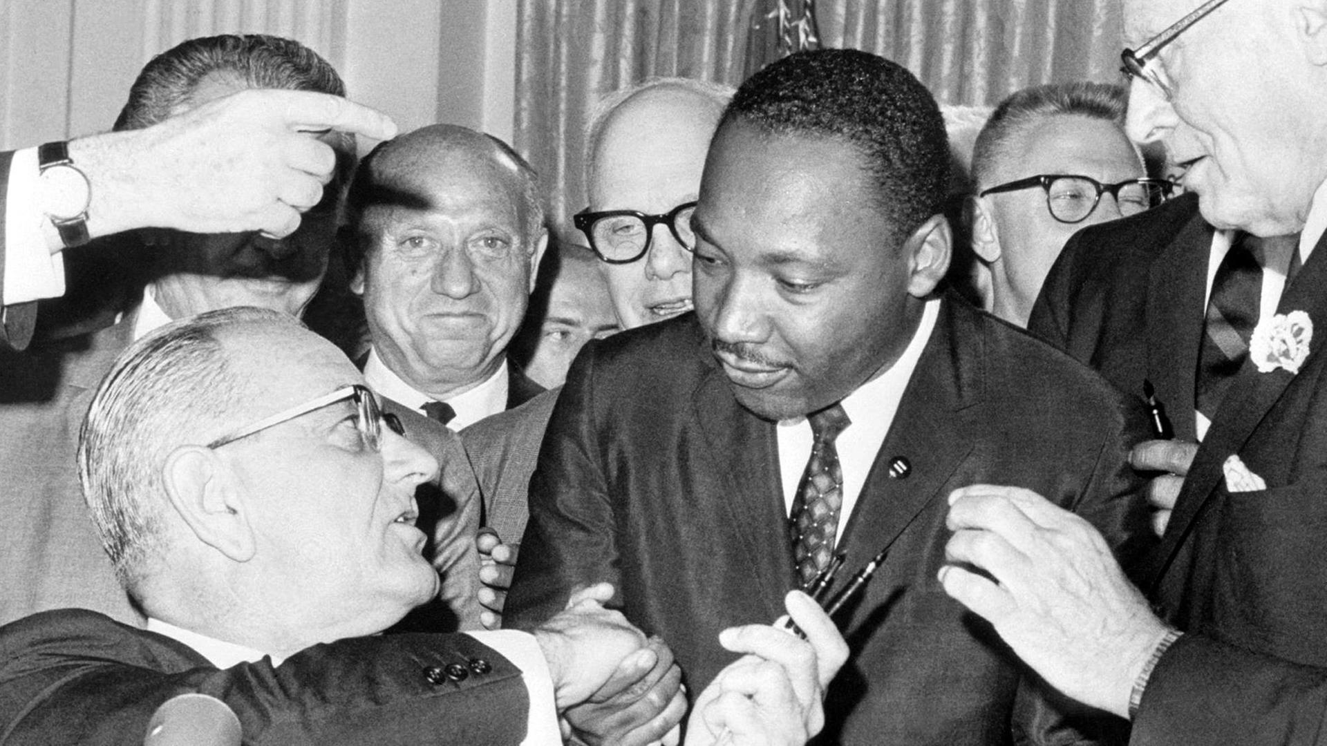 Nach der Unterzeichnung des Bürgerrechts-Gesetzes am 2.7.1964 in Washington DC. reicht US-Präsident Lyndon Baines Johnson (l) den Federhalter an den Bürgerrechtler Martin Luther King weiter und gibt ihm die Hand. Das Bürgerrechtsgesetz sollte eine Gleichberechtigung der farbigen Bevölkerung in den Vereinigten Staaten von Amerika garantieren und galt als eine der wichtigsten Gesetzes-Entscheidungen in der Geschichte der USA. King wurde am 4.4.1968 im Alter von 39 Jahren in Memphis von James Earl Ray erschossen.