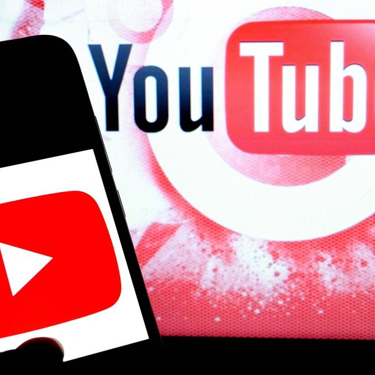Handy mit Youtube-Logo vor einer Leinwand, die ebenfalls das Youtube-Logo zeigt