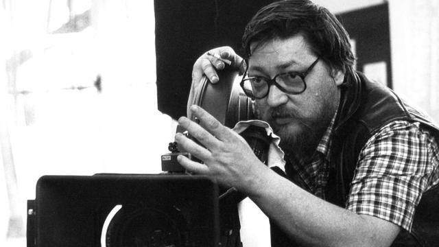 Schwarz-weißes Foto des Regisseurs Rainer Werner Fassbinder bei Dreharbeiten.