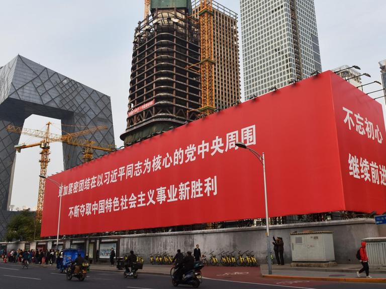 Eine großer Werbekubus in Peking vor eine großen Baustelle.