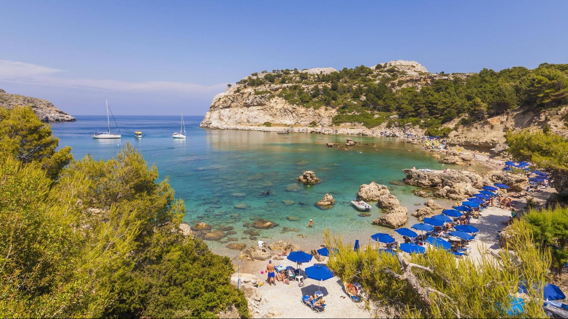 Liegen und Sonnenschirme stehen für Touristen am Anthony Quinn Bay auf Rhodos bereit. Liegen und Sonnenschirme stehen für Touristen am Anthony Quinn Bay auf Rhodos bereit.