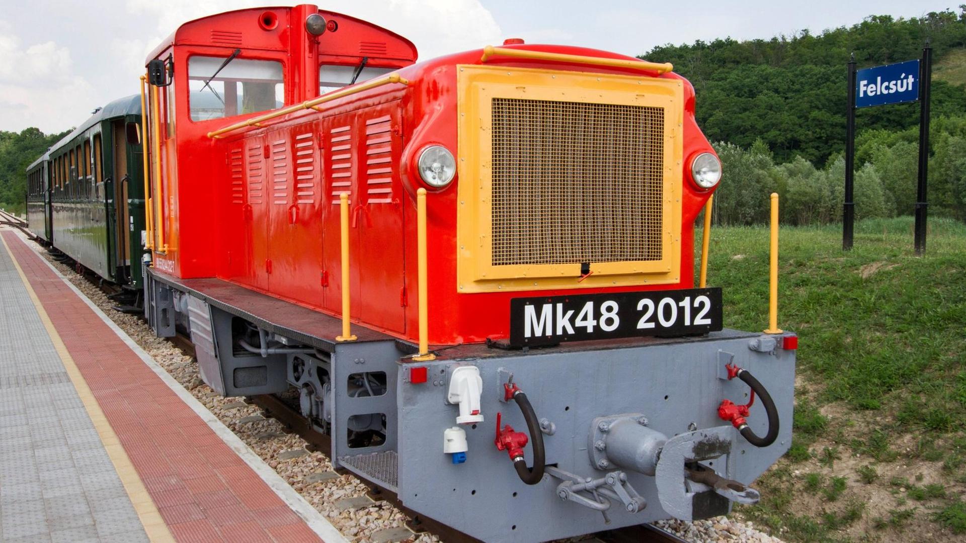 Die von einer roten Lokomotive gezogene Schmalspurbahn am Bahnhof steht am Bahnhof von Felcsút in Ungarn.