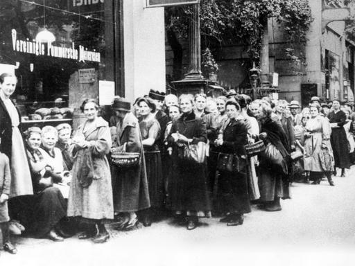 Hunger an der Heimatfront: Frauen und Kinder stehen 1917 in Berlin Schlange an einem Lebensmittelgeschäft. Im Januar 1915 war zunächst Brot rationiert worden, es folgten weitere Lebensmittel.
