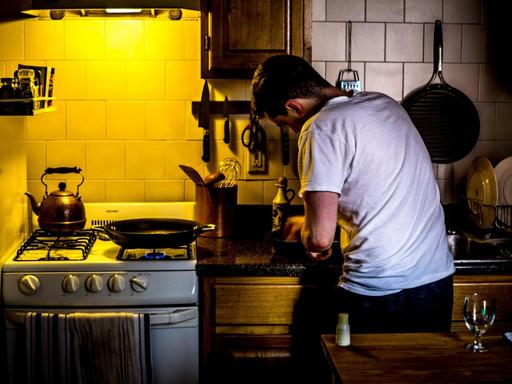 Das Bild zeigt einen Mann in einer kleinen Küche. Food Podcasts sind besonders bei Hobbyköchen beliebt – auch als Nebenbeibeschallung in der Küche.