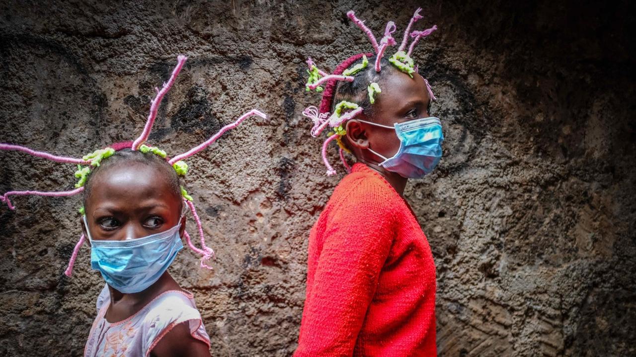 Die Mächen tragen einzelne, rosafarben und grün umwickelte Zöpfchen, die gerade vom Kopf abstehen und an die Form des Coronavirus erinnern sollen. Die Mächen tragen einzelne, rosafarben und grün umwickelte Zöpfchen, die gerade vom Kopf abstehen und an die Form des Coronavirus erinnern sollen.