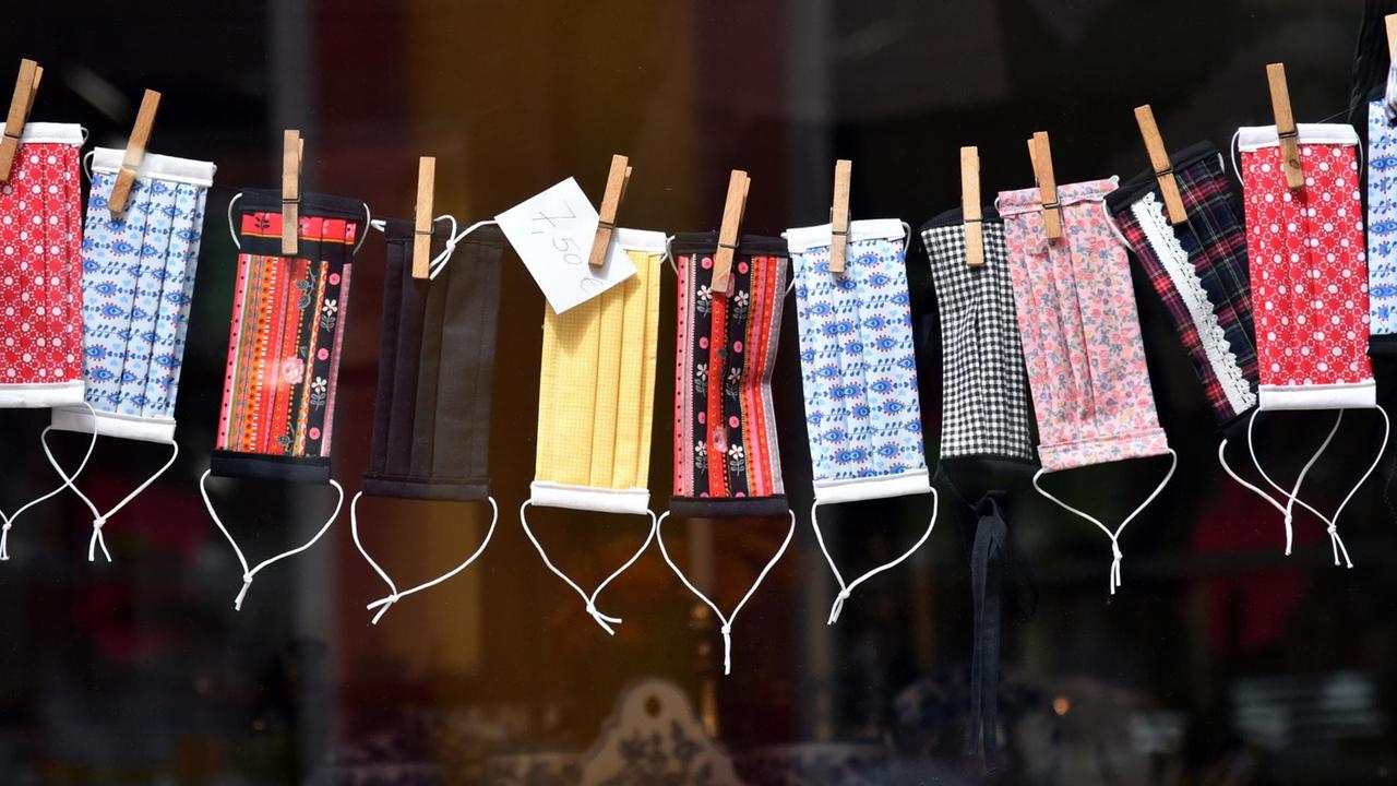 Mund-Nase-Masken zum Schutz vor dem Coronavirus in einem Schaufenster in Erfurt (Thüringen). Die bunt gemusterten Masken sind an einer Wäscheleine aufgehängt. Mund-Nase-Masken zum Schutz vor dem Coronavirus in einem Schaufenster in Erfurt (Thüringen). Die bunt gemusterten Masken sind an einer Wäscheleine aufgehängt.