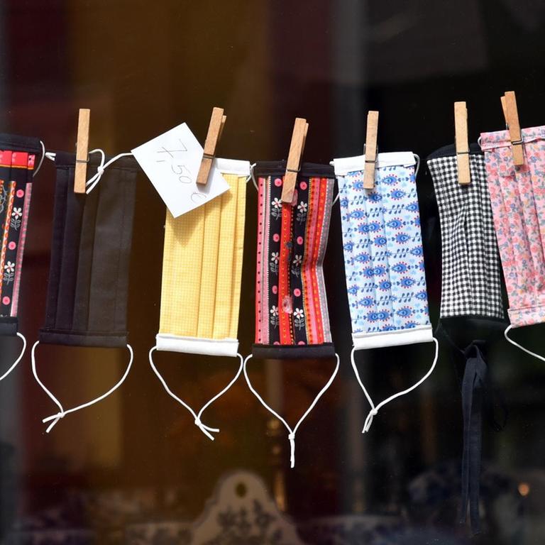 Mund-Nase-Masken zum Schutz vor dem Coronavirus in einem Schaufenster in Erfurt (Thüringen). Die bunt gemusterten Masken sind an einer Wäscheleine aufgehängt.