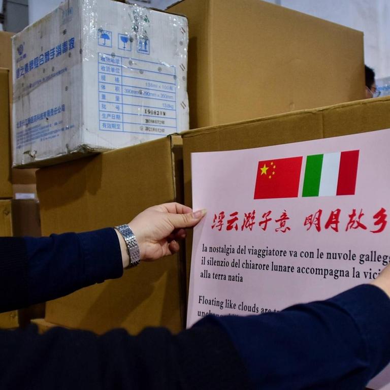 In China wird ein Schild mit einer chinesischen und einer italienischen Flagge auf ein Hilfspaket in der Corona-Krise geklebt.