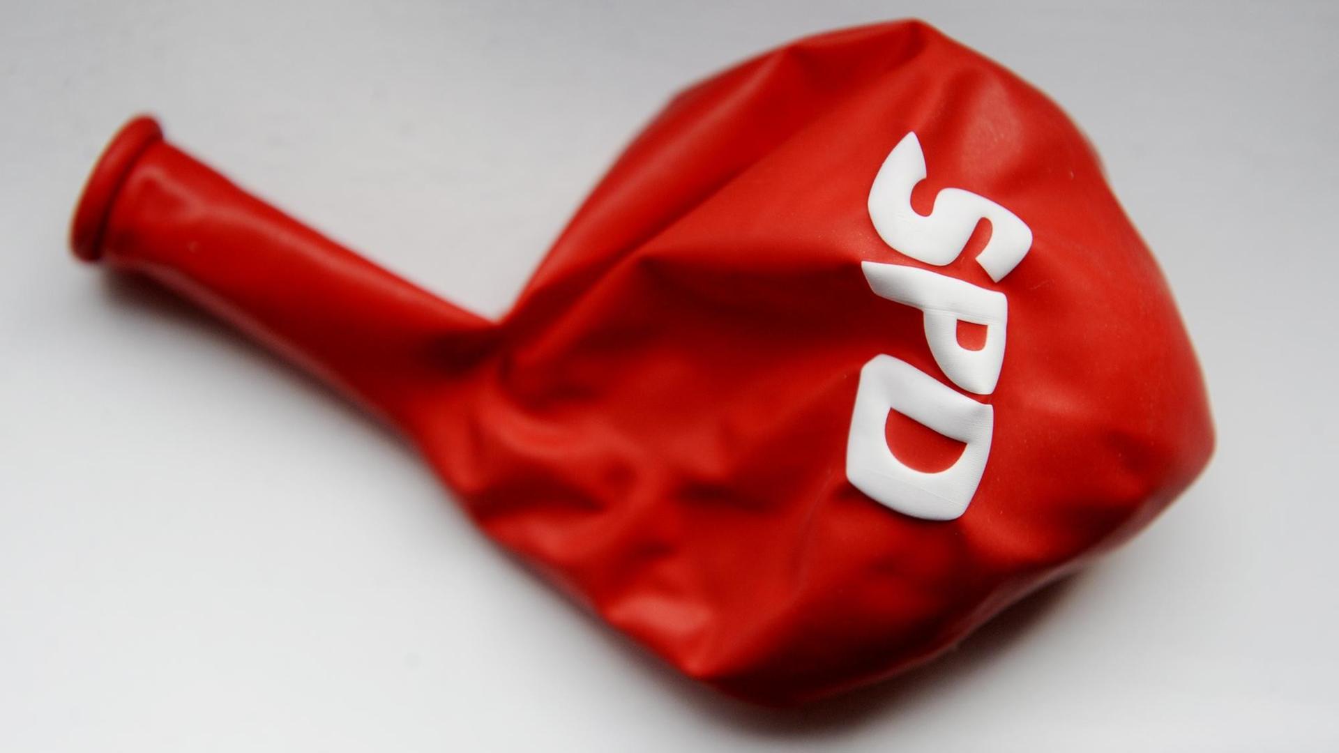 Ein leerer roter Luftballon mit der Aufschrift SPD liegt auf einem weißen Untergrund. Ein leerer roter Luftballon mit der Aufschrift SPD liegt auf einem weißen Untergrund.