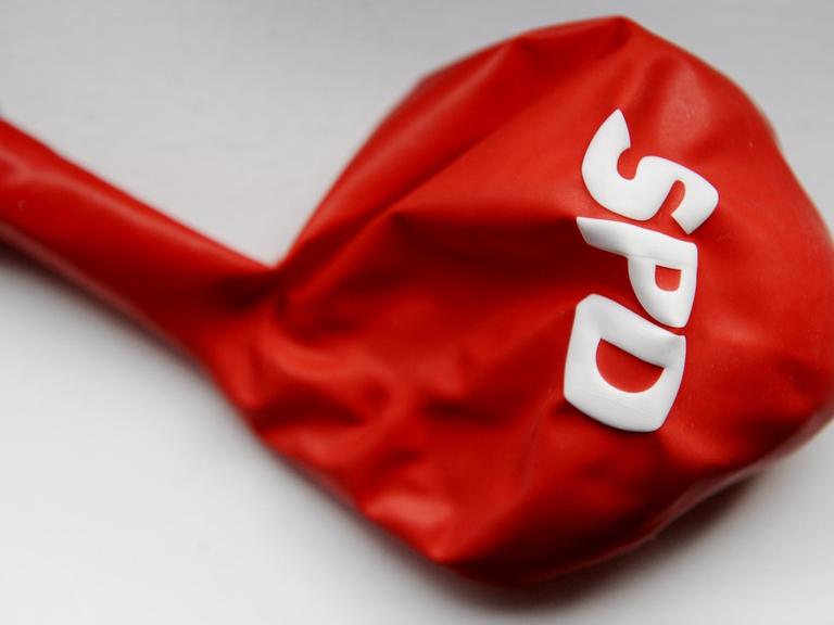 Ein leerer roter Luftballon mit der Aufschrift SPD liegt auf einem weißen Untergrund.