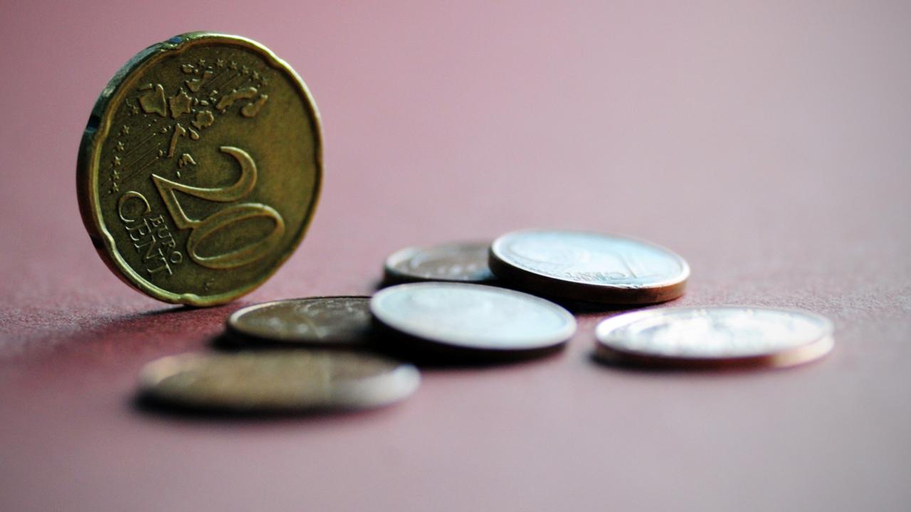 Mehrere Euro-Münzen, eine 20-Cent-Münze steht aufrecht