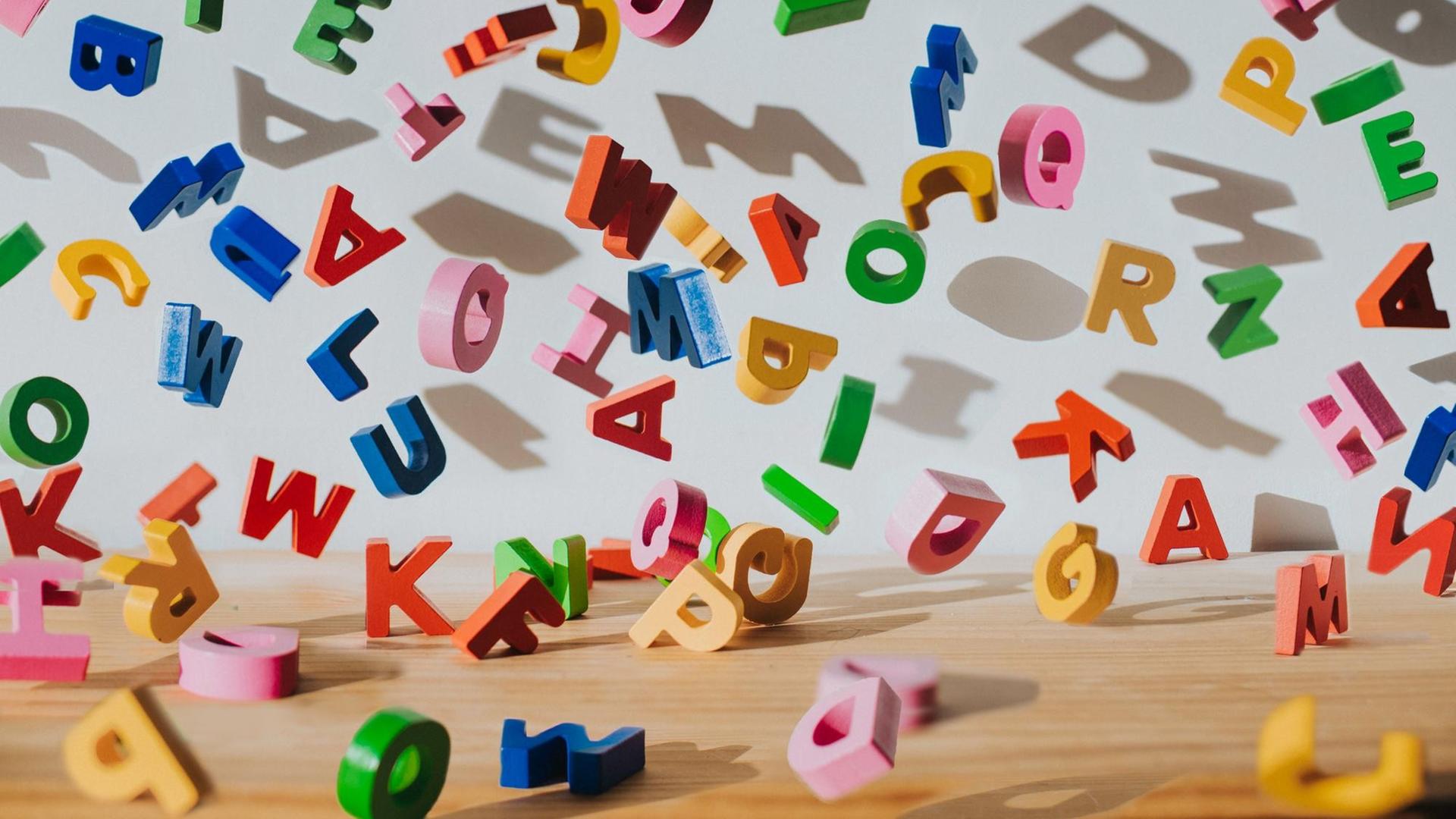 Farbige fliegende Buchstaben vor einer weißen Wand. Farbige fliegende Buchstaben vor einer weißen Wand.