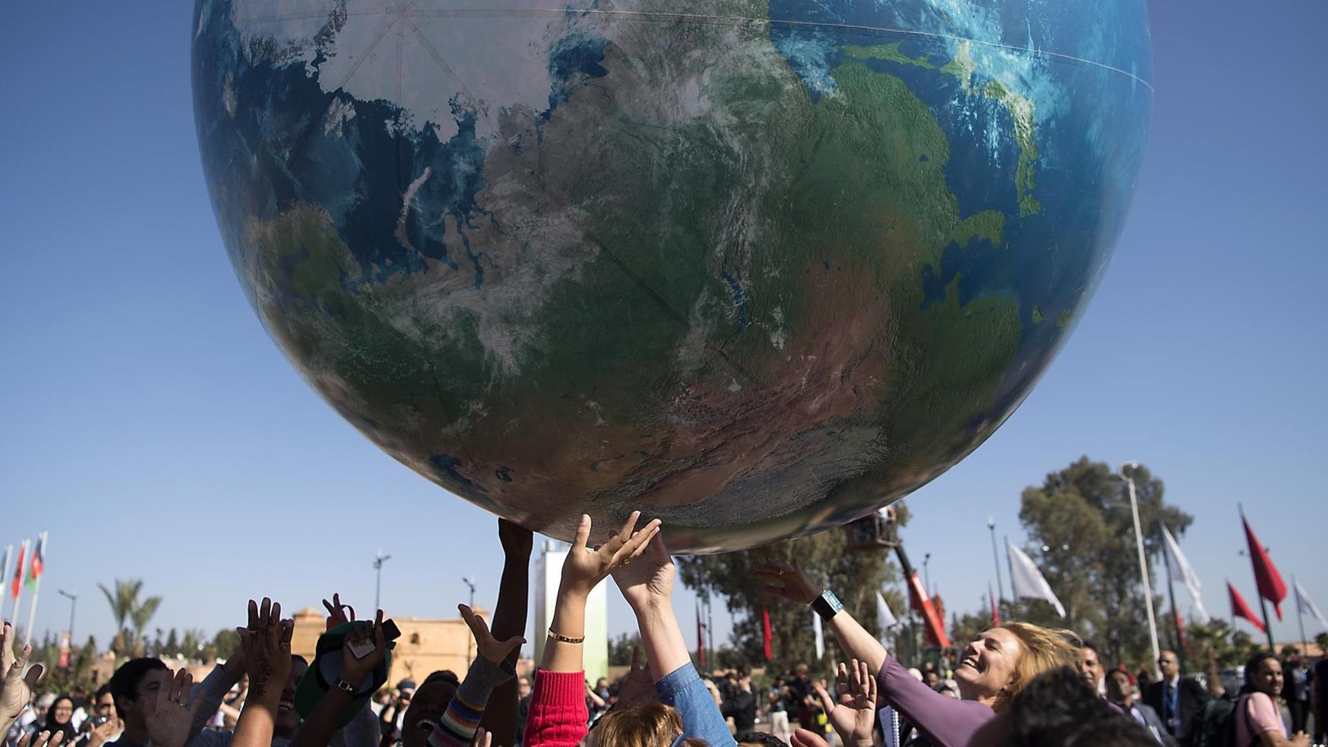Teilnehmer der Internationalen Klimakonferenz in Marrakesch spielen mit einem riesigen aufgeblasenen Globus Teilnehmer der Internationalen Klimakonferenz in Marrakesch spielen mit einem riesigen aufgeblasenen Globus