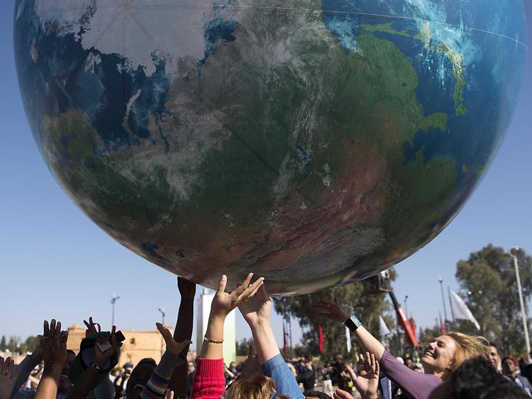Teilnehmer der Internationalen Klimakonferenz in Marrakesch spielen mit einem riesigen aufgeblasenen Globus