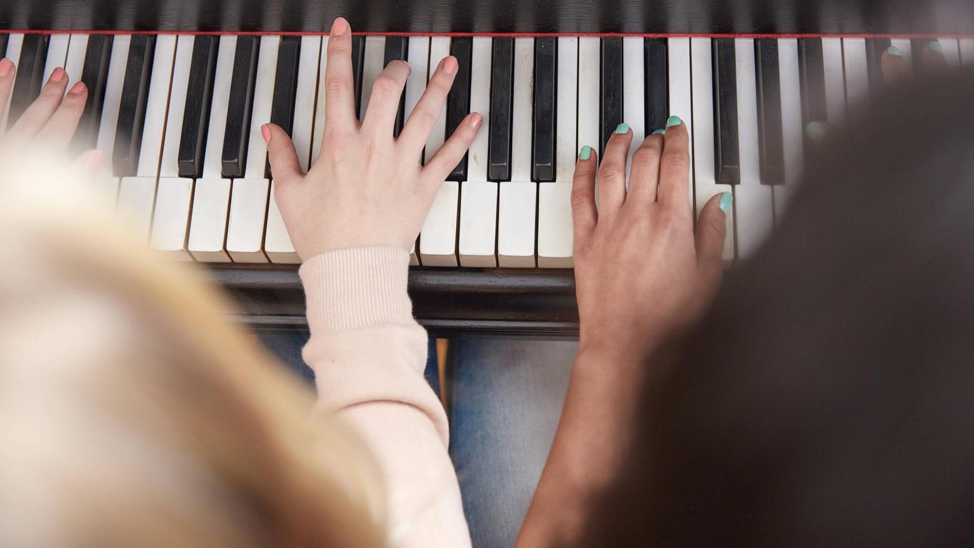 Zwei Hände von verschiedenen Menschen auf einer Klaviertastatur