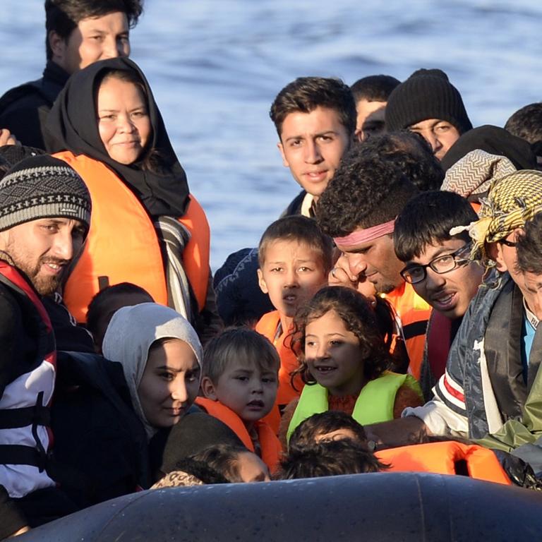 Kinder, Frauen und Männer in Rettungswesten auf einem Schlauchboot. 