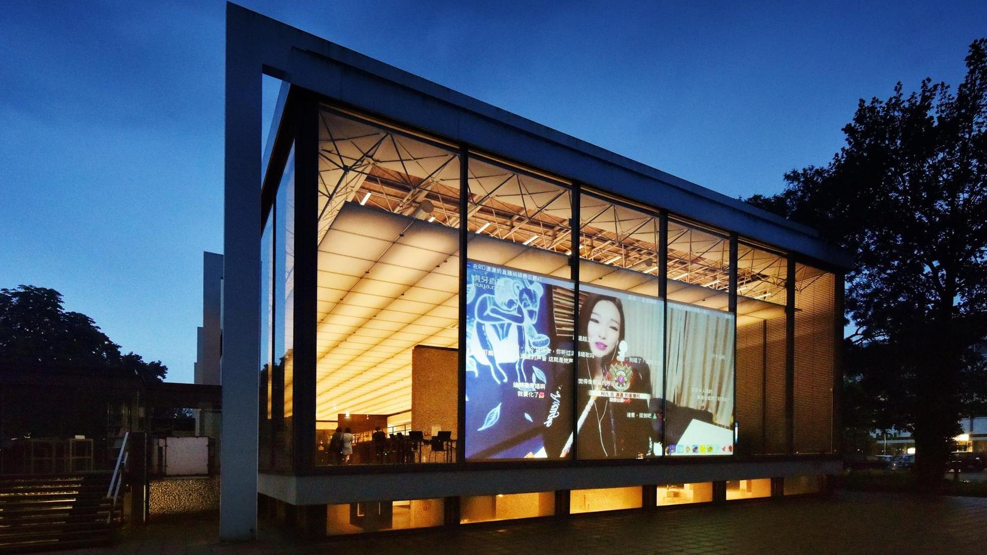 Das Lehmbruck Museum von außen, auf der Glasfassade ist eine projezierte Filmszene von Xu Bing zu sehen