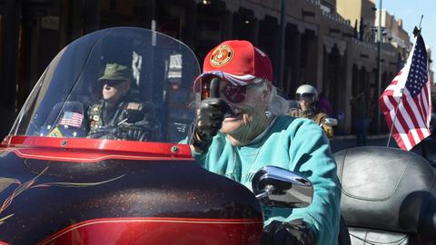 Eine ältere Frau, die einen Hut des US-Marinekorps trägt, streckt den Daumen hoch, als sie mit ihrem Motorrad an einer Parade zum Veteranentag in Santa Fe, New Mexico, teilnimmt.