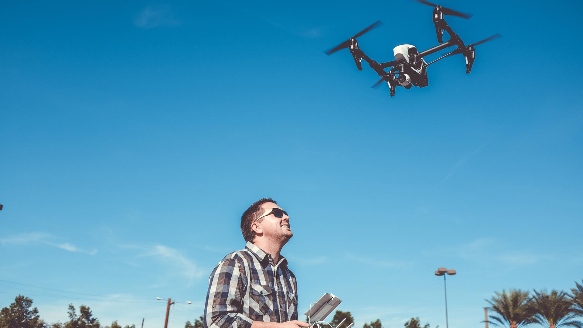 Ein Mann steuert eine mit Kamera bestückte Drohne.