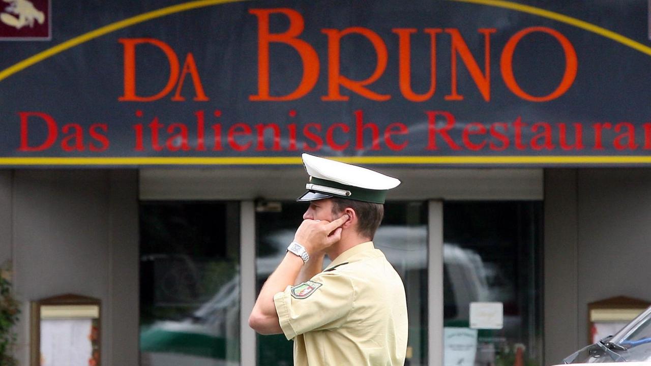 Der Polizist steht vor dem Eingang eines Pizza-Restaurants namens "Da Bruno" nahe des Tatorts.