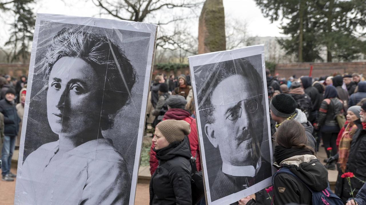 Demonstranten stehen 2018 mit Bildern von Rosa Luxemburg und Karl Liebknecht anlässlich des 99. Jahrestages ihrer Ermordung vor der Gedenkstätte der Sozialisten in Berlin-Friedrichsfelde. Demonstranten stehen 2018 mit Bildern von Rosa Luxemburg und Karl Liebknecht anlässlich des 99. Jahrestages ihrer Ermordung vor der Gedenkstätte der Sozialisten in Berlin-Friedrichsfelde.