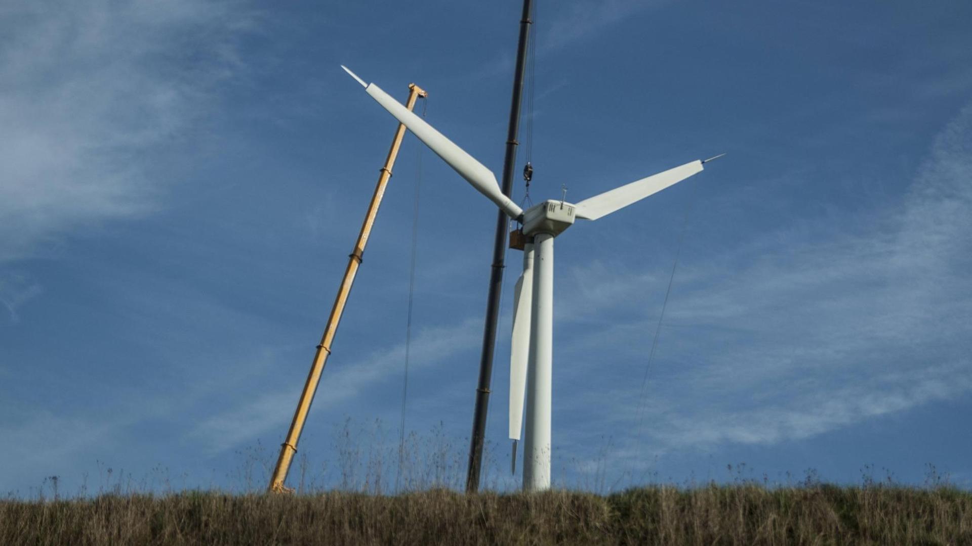 Zwei große Kräne stehen neben einem Windrad, das abgebaut werden soll Zwei große Kräne stehen neben einem Windrad, das abgebaut werden soll