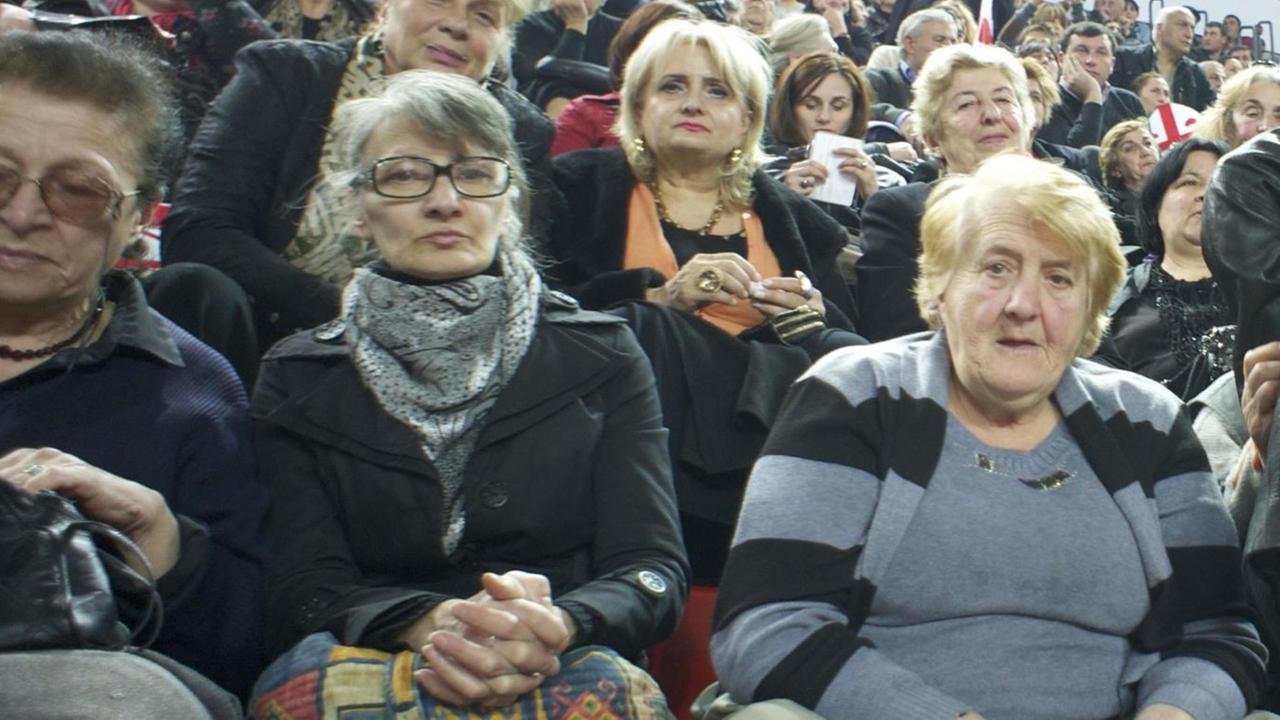 Viele Frauen sitzen in Reihen hintereinander und schauen in die Kamera. Viele Frauen sitzen in Reihen hintereinander und schauen in die Kamera.
