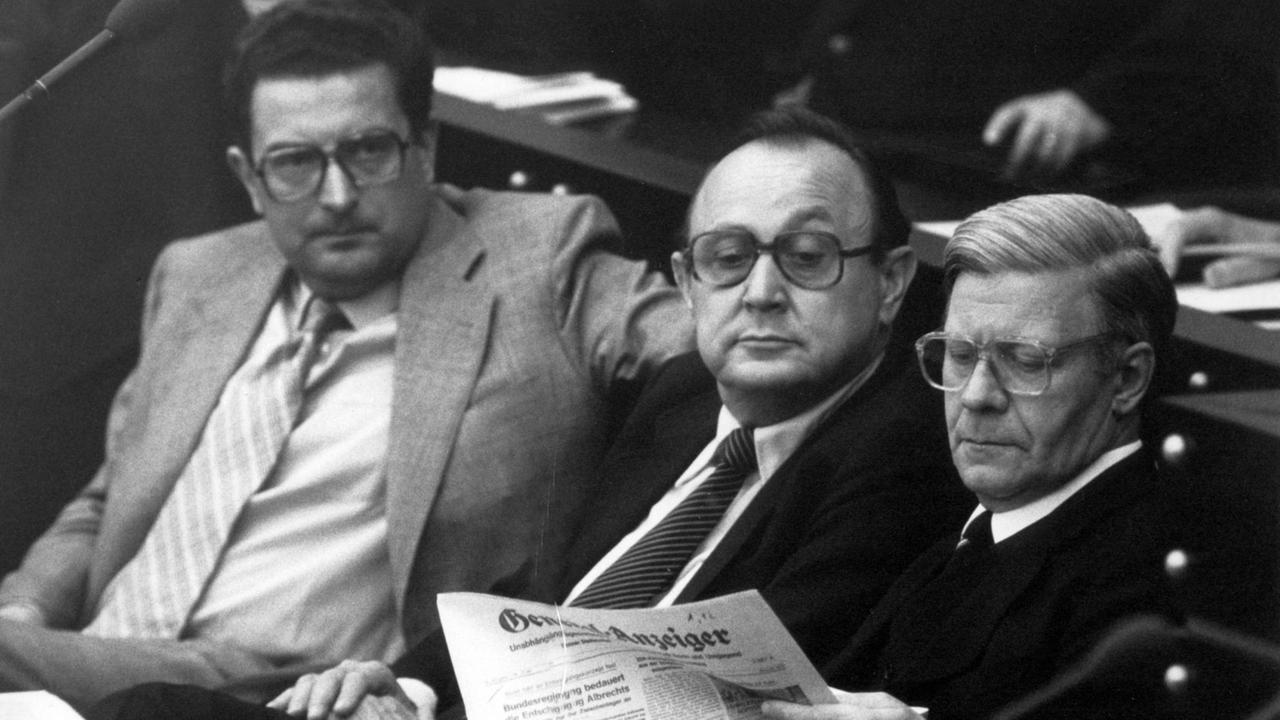 Bundeskanzler Helmut Schmidt (SPD, r) sitzt 1980 auf der Regierungsbank im Bonner Bundestag und liest den General-Anzeiger. Bundesaußenminister Hans Dietrich Genscher (FDP, M) liest mit. Links Innenminister Gerhart Baum (FDP).