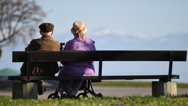 Zwei Senioren sitzen an der Uferpromenade in Langenargen (Baden-Württemberg) auf einer Parkbank.