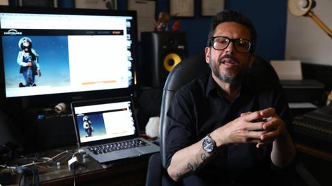 Der Komponist Felipe Perez Santiago bei einem Interview in Mexico City. Im Hintergrund ist ein Rechner mit Monitor zu sehen. Perez Santiago trägt eine schwarze Brille.