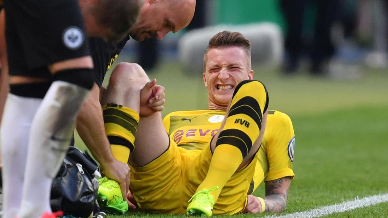 Dortmunds Marco Reus wird am Spielfeldrand behandelt. Dortmunds Marco Reus wird am Spielfeldrand behandelt.