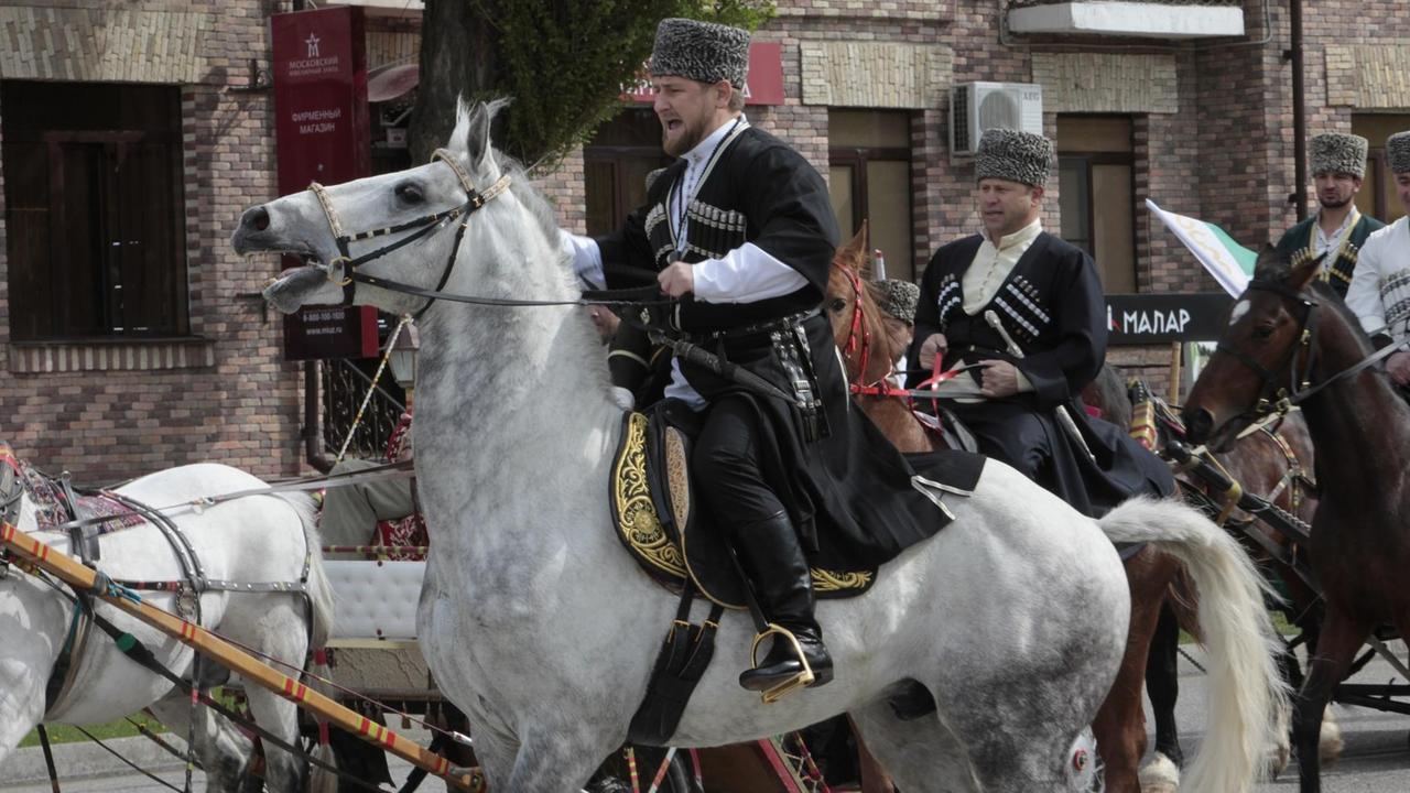 Ein Mann in traditioneller Kleidung reitet auf einem Pferd.