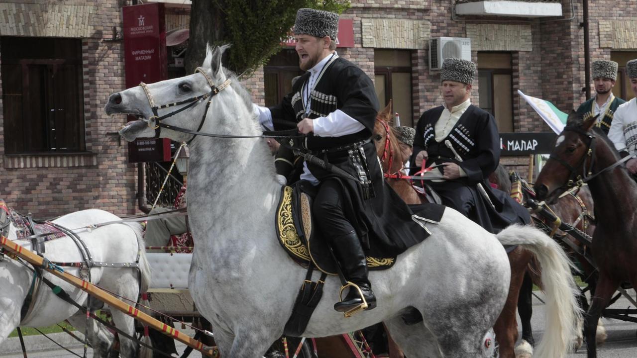 Ein Mann in traditioneller Kleidung reitet auf einem Pferd. Ein Mann in traditioneller Kleidung reitet auf einem Pferd.
