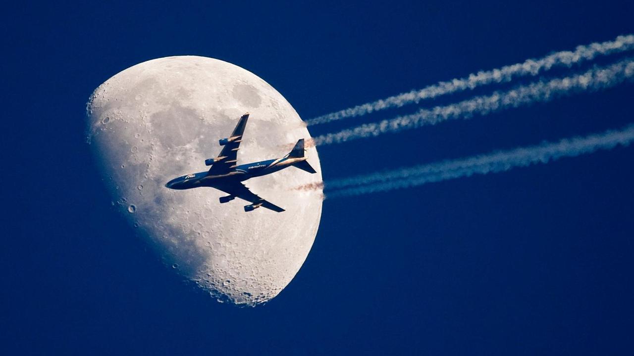 Ein Flugzeug fliegt über dem brandenburgischen Sieversdorf (Oder-Spree) scheinbar ganz nah am Mond vorbei. Ein Flugzeug fliegt über dem brandenburgischen Sieversdorf (Oder-Spree) scheinbar ganz nah am Mond vorbei.