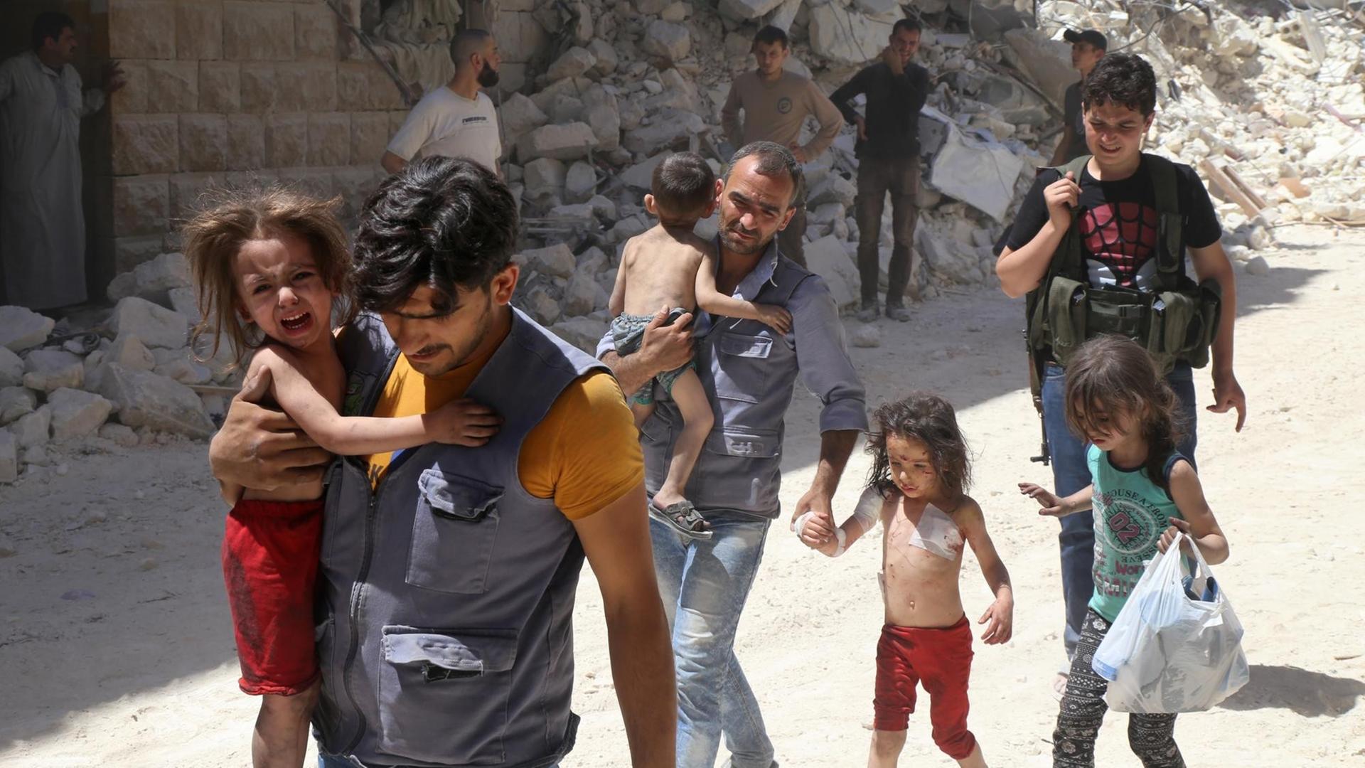 Syrische Männer tragen weinende Kinder zwischen den Trümmern der zerstörten Stadt Aleppo in Syrien. Syrische Männer tragen weinende Kinder zwischen den Trümmern der zerstörten Stadt Aleppo in Syrien.