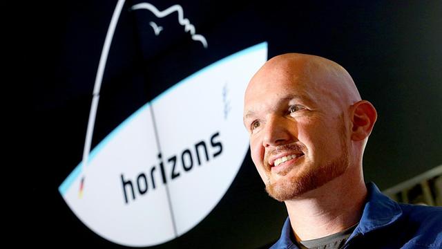 Der Astronaut Alexander Gerst steht vor dem Logo seiner Weltraummission "Horizons"