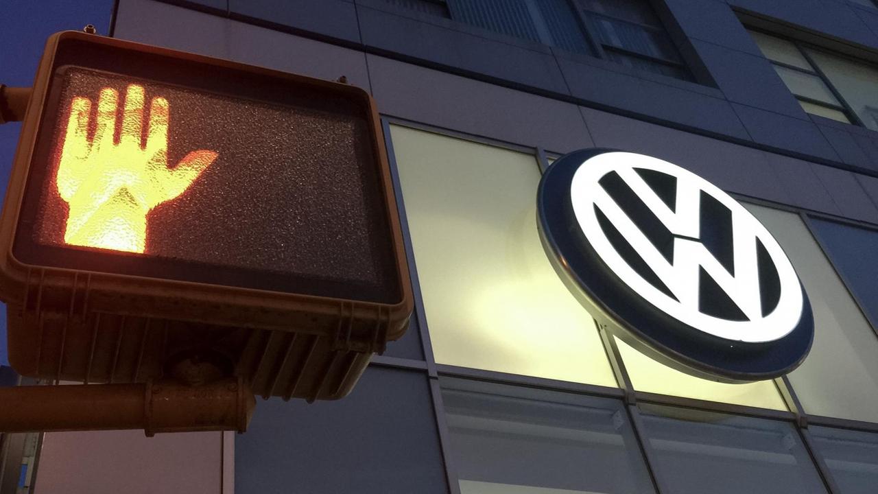 In New York leuchtet das Logo einer VW-Niederlassung neben einer Fußgängerampel.