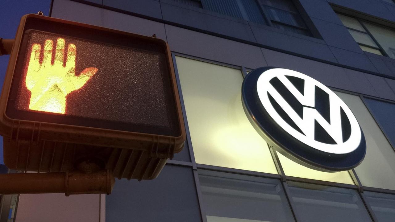 In New York leuchtet das Logo einer VW-Niederlassung neben einer Fußgängerampel. In New York leuchtet das Logo einer VW-Niederlassung neben einer Fußgängerampel.
