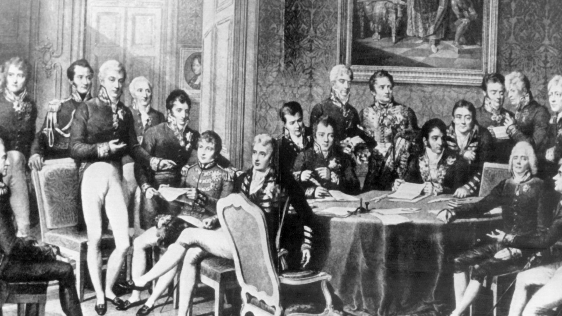 Der österreichische Staatsmann versuchte durch Kongreßdiplomatie, die vorrevolutionäre politische und soziale Ordnung in Europa wiederherzustellen. Er bekämpfte alle liberalen und revolutionären Bewegungen. Klemens Wenzel Fürst von Metternich wurde am 15. Mai 1773 in Koblenz geboren und ist am 11. Juni 1859 in Wien gestorben. Die zeitgenössische Darstellung zeigt stehend (l-r): Wellington, Lobo da Silveira, Saldanha da Gama, Löwenhjelm, Noailles, Metternich, La Tour du Pin, Nesselrode, Dalberg, Rasumofsky, Stewart, Clancarty, Wacken, Gentz, Humbold, Cathcart sowie sitzend (l-r): Hardenberg, Palmella, Castlereagh, Wessenberg, Labrador, Talleyrand und Stackelberg. Der österreichische Staatsmann versuchte durch Kongreßdiplomatie, die vorrevolutionäre politische und soziale Ordnung in Europa wiederherzustellen. Er bekämpfte alle liberalen und revolutionären Bewegungen. Klemens Wenzel Fürst von Metternich wurde am 15. Mai 1773 in Koblenz geboren und ist am 11. Juni 1859 in Wien gestorben. Die zeitgenössische Darstellung zeigt stehend (l-r): Wellington, Lobo da Silveira, Saldanha da Gama, Löwenhjelm, Noailles, Metternich, La Tour du Pin, Nesselrode, Dalberg, Rasumofsky, Stewart, Clancarty, Wacken, Gentz, Humbold, Cathcart sowie sitzend (l-r): Hardenberg, Palmella, Castlereagh, Wessenberg, Labrador, Talleyrand und Stackelberg.