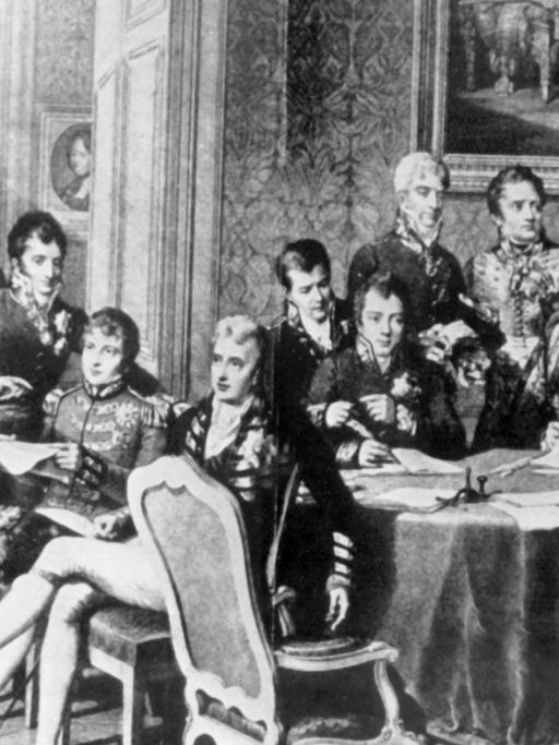 Der österreichische Staatsmann versuchte durch Kongreßdiplomatie, die vorrevolutionäre politische und soziale Ordnung in Europa wiederherzustellen. Er bekämpfte alle liberalen und revolutionären Bewegungen. Klemens Wenzel Fürst von Metternich wurde am 15. Mai 1773 in Koblenz geboren und ist am 11. Juni 1859 in Wien gestorben. Die zeitgenössische Darstellung zeigt stehend (l-r): Wellington, Lobo da Silveira, Saldanha da Gama, Löwenhjelm, Noailles, Metternich, La Tour du Pin, Nesselrode, Dalberg, Rasumofsky, Stewart, Clancarty, Wacken, Gentz, Humbold, Cathcart sowie sitzend (l-r): Hardenberg, Palmella, Castlereagh, Wessenberg, Labrador, Talleyrand und Stackelberg.