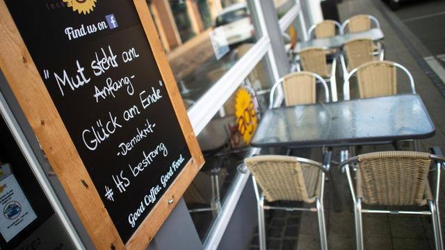 Ein Schild mit der Aufschrift "Mut steht am Anfang - Glück am Ende. #HSbestrong" steht an einem Café in der Fußgängerzone in Heinsberg.