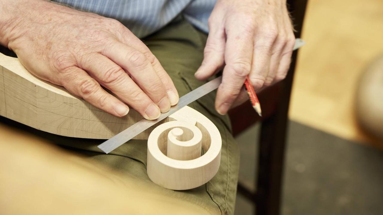 Geigenbauer arbeitet mit Holz an der sogenannten Schnecke Geigenbauer arbeitet mit Holz an der sogenannten Schnecke