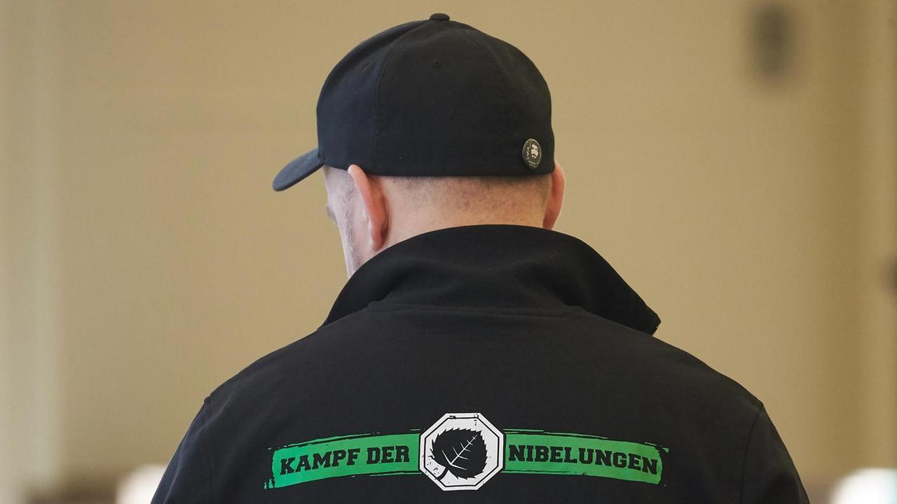 Das Foto zeigt in der Rückansicht einen der Angeklagten im Verfahren gegen mutmaßliche Mitglieder des «Aktionsbüros Mittelrhein». Sein Shirt trägt die Aufschrift "Kampf der Nibelungen - Disziplin ist alles!". Das Foto zeigt in der Rückansicht einen der Angeklagten im Verfahren gegen mutmaßliche Mitglieder des «Aktionsbüros Mittelrhein». Sein Shirt trägt die Aufschrift "Kampf der Nibelungen - Disziplin ist alles!".