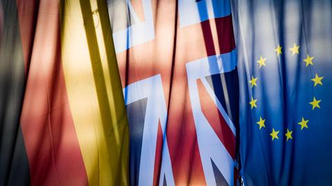 Eine deutsche, eine britische und eine europäische Flagge hängen nebeneinander.