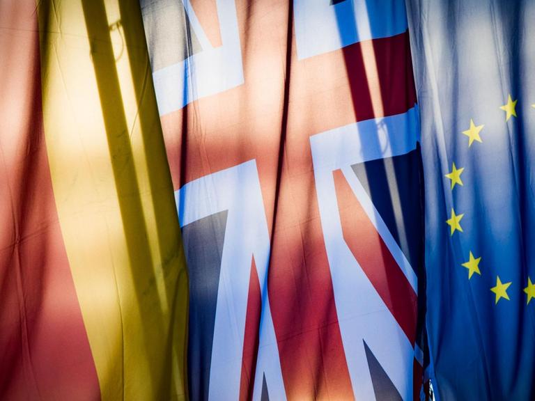 Eine deutsche, eine britische und eine europäische Flagge hängen nebeneinander.