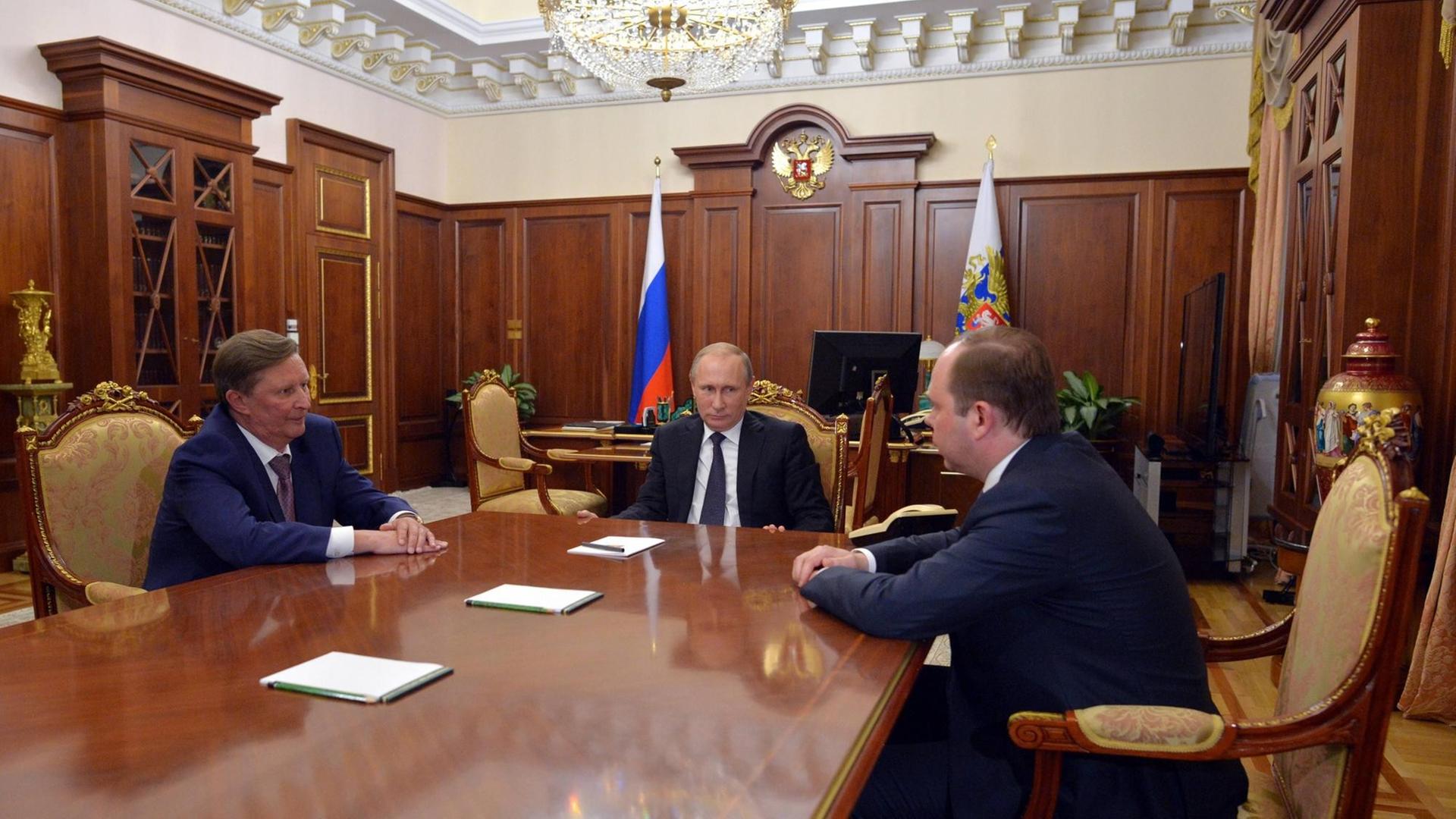 Wladimir Putin sitzt mit Anton Waino und Sergej Iwanow an einem Tisch in einem Büro des Kreml