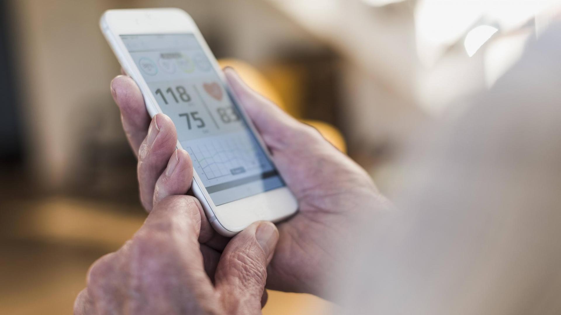 Älterer Mann schaut auf sein Smartpone, das Blutdruckwerte anzeigt. Älterer Mann schaut auf sein Smartpone, das Blutdruckwerte anzeigt.