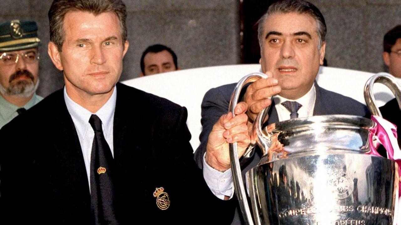Trainer Jupp Heynckes und Lorenzo Sanz (r.), Präsident des spanischen Rekordmeisters Real Madrid, haben ihre Hände an der Trophäe der europäischen Champions League, als sie am 21. Mai am Madrider Flughafen Barajas ankommen. Am Vortag gewann der Verein das Europapokal-Endspiel in Amsterdam mit 1:0 gegen Juventus Turin. Trainer Jupp Heynckes und Lorenzo Sanz (r.), Präsident des spanischen Rekordmeisters Real Madrid, haben ihre Hände an der Trophäe der europäischen Champions League, als sie am 21. Mai am Madrider Flughafen Barajas ankommen. Am Vortag gewann der Verein das Europapokal-Endspiel in Amsterdam mit 1:0 gegen Juventus Turin.